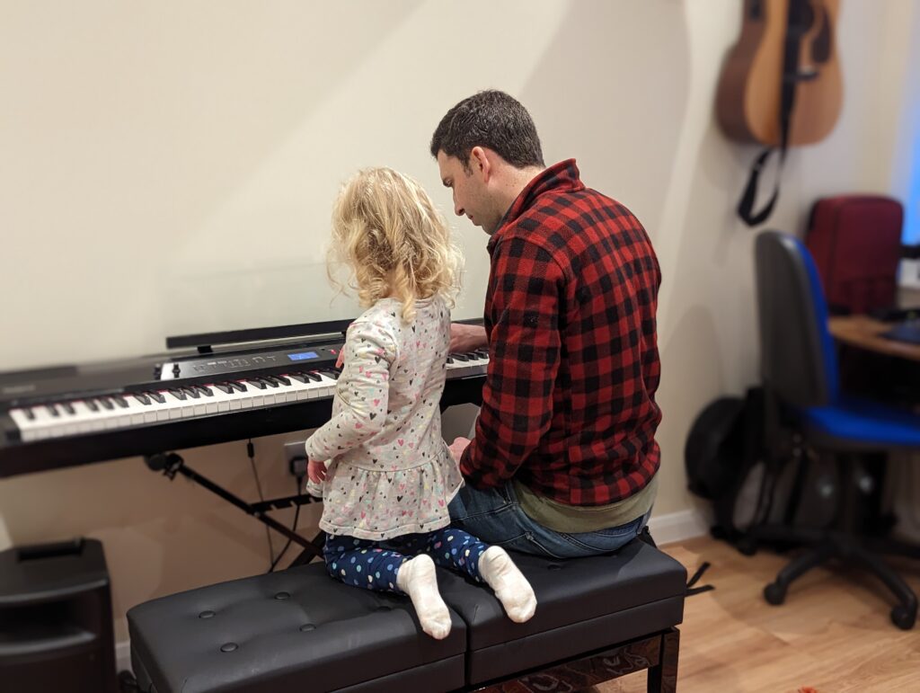 Hugh helps a young student at the piano